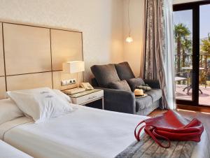 a hotel room with a bed, chair, and nightstand at B bou Hotel La Viñuela & Spa in Viñuela