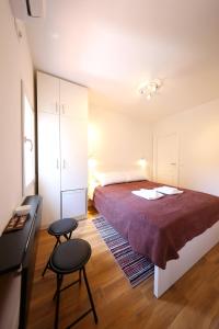 1 dormitorio con 1 cama y 2 taburetes en Pyrotima Apartments, en Zadar