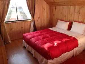 una cama roja en una habitación con ventana en Hostal Monica, en Pucón