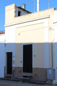 a white building with a black door on the side of it at A Casa di Anna in Specchia