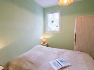 a bedroom with a bed with a window and a book on it at Apartment Les Caraïbes-3 by Interhome in Le Grau-du-Roi