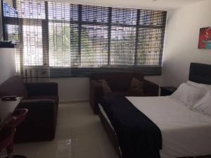 1 dormitorio con cama, sofá y ventanas en SPACIOUS STUDIO CENTRAL LOCATION (201) en Bogotá