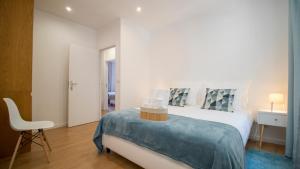 a white bedroom with a bed and a chair at Oporto Yellow Villas in Porto