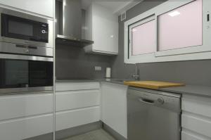 cocina con armarios blancos y microondas en Apartment Ronda Sant Antoni, en Girona