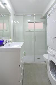 a white bathroom with a shower and a washing machine at Apartment Ronda Sant Antoni in Girona