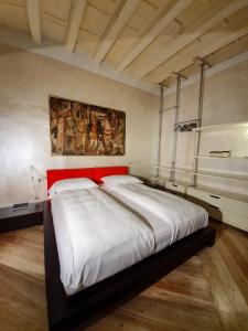 un grande letto in una stanza con un dipinto sul muro di Flora Inn Flora I - Appartamento nel cuore di Piazza Vecchia a Bergamo