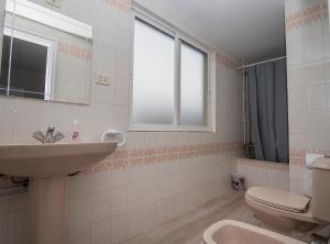 a bathroom with a sink and a toilet and a window at AMPLIO APARTAMENTO EN BURELA in Burela de Cabo