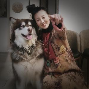 Uma mulher está sentada ao lado de um cão. em Guixu Huatang Homestay em Qinhuangdao