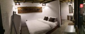 une chambre avec un lit avec des draps blancs et des oreillers dans l'établissement Guixu Huatang Homestay, à Qinhuangdao
