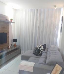 uma sala de estar com um sofá e uma televisão em Apartamento 2 quartos a 4 minutos do mar de Maceió em Maceió
