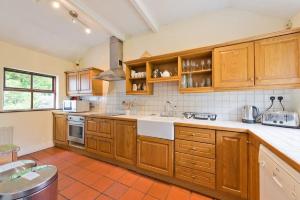 una cocina con armarios de madera y fregadero en The Bunker Cottage, Baltray en Drogheda