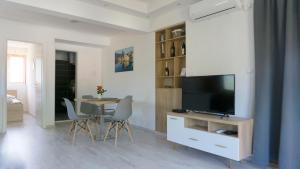 Apartments Ena في تريبينيي: غرفة معيشة مع تلفزيون وطاولة مع كراسي