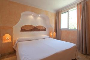 a bedroom with a white bed with a head board at Résidence Domaine De Caranella in Porto-Vecchio