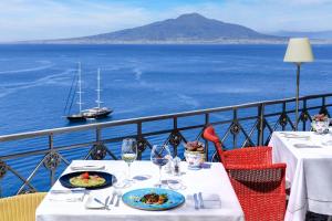 stół z dwoma talerzami jedzenia i widokiem na ocean w obiekcie Grand Hotel Ambasciatori w Sorrento