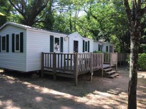 a white cabin with a wooden deck in the woods at Camping la Rouvière in Chame