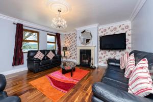 sala de estar con sofá de cuero negro y TV en Harbour View Lodge, en Kenmare