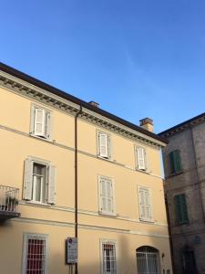 a yellow building with white windows on a street at IL VICOLETTO Appartamento vacanza in Cesena