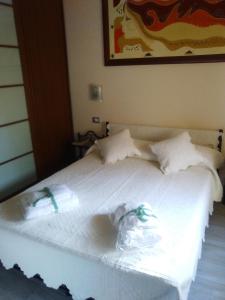 un letto bianco con lenzuola e cuscini bianchi di Sardinia Holidays - Domus Patrizia a Quartu SantʼElena