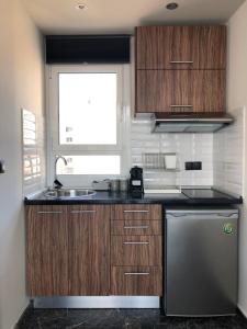 a kitchen with wooden cabinets and a sink and a window at Ladadika 5th Floor in Thessaloniki