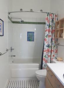 a white bathroom with a shower and a toilet at Simply Charming Cottages in Cavendish