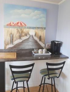 a painting of a boardwalk with an umbrella and two chairs at Simply Charming Cottages in Cavendish