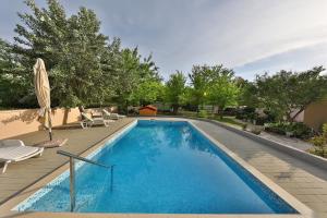 a swimming pool with chairs and an umbrella at Mobile Home Grbe in Nin