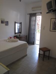 a bedroom with a bed and a dresser and a television at Eden Ios Rooms in Mylopotas