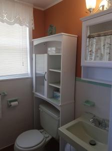 a bathroom with a white toilet and a sink at Simply Charming Cottages in Cavendish