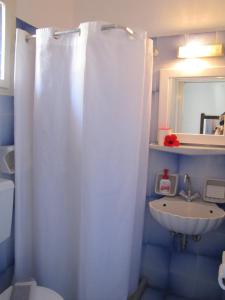 a bathroom with a white shower curtain and a sink at Eden Ios Rooms in Mylopotas