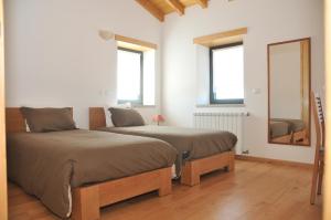 two beds in a room with two windows and a mirror at Casa do Cabeco in Seia