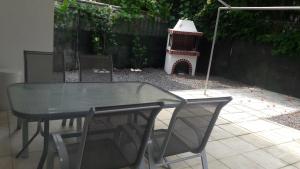 uma mesa de vidro e cadeiras num quintal com uma casa de pássaros em Friends 2 Apartment em Perea