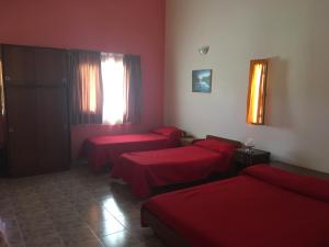 a room with three beds with red sheets at Departamento Carlos paz in Villa Carlos Paz