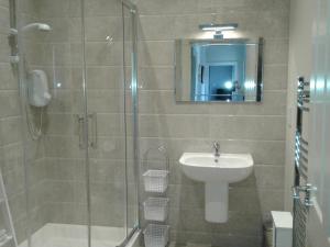 ein Bad mit einer Dusche und einem Waschbecken in der Unterkunft Necarne Manor Apartment in Irvinestown