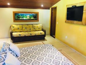 a living room with a couch and a flat screen tv at Aldeia do Bambu Camping e Chalés in Quartéis