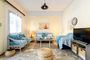 ein Wohnzimmer mit blauen Stühlen und einem TV in der Unterkunft Makrygialos sun and sea home in Makry Gialos