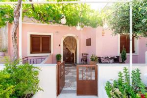 ein rosafarbenes Haus mit einem Innenhof mit Tischen und Stühlen in der Unterkunft Makrygialos sun and sea home in Makry Gialos