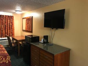 a hotel room with a desk with a television on the wall at Travel Inn Weatherford in Weatherford