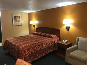 a hotel room with a bed and a chair at Travel Inn Weatherford in Weatherford