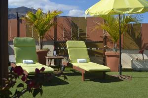 two green chairs and a table and an umbrella at Apartamento Vacacional Relax frente al mar in Candelaria