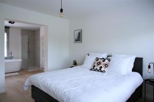 - une chambre blanche avec un grand lit et une baignoire dans l'établissement Brygga, à Bruges