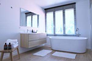 a white bathroom with a tub and a sink at Brygga in Bruges +18 photos