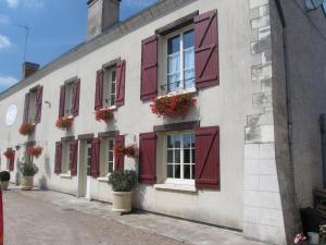 ein Gebäude mit roten Fensterläden und Blumen darauf in der Unterkunft Les Bords de Loire in Veuves