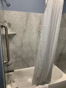 a bathroom with a shower with a white shower curtain at Scottish Inns and Suites Scarsdale in Houston