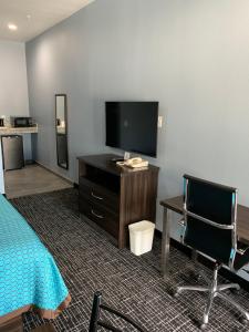 a hotel room with a bed and a tv and a desk at Scottish Inns and Suites Scarsdale in Houston