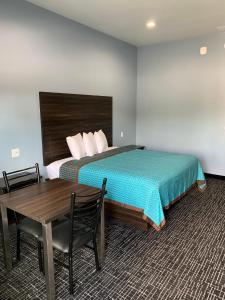 1 dormitorio con cama, mesa, mesa y silla en Scottish Inns and Suites Scarsdale en Houston