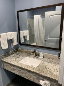 a bathroom with a sink and a large mirror at Scottish Inns and Suites Scarsdale in Houston