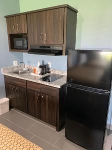 a kitchen with a black refrigerator and a sink at Scottish Inns and Suites Scarsdale in Houston
