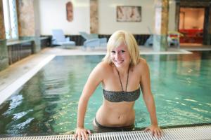 
a beautiful young woman in a bikini sitting on a swimming pool at Häcker´s Grand Hotel in Bad Ems
