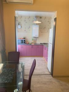een keuken met paarse kasten en een glazen tafel bij Александра Поля проспект Апартаменты in Dnipro