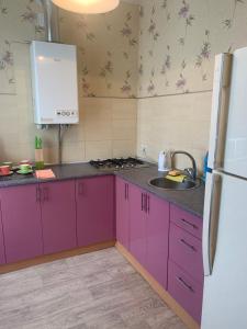 a kitchen with purple cabinets and a white refrigerator at Александра Поля проспект Апартаменты in Dnipro